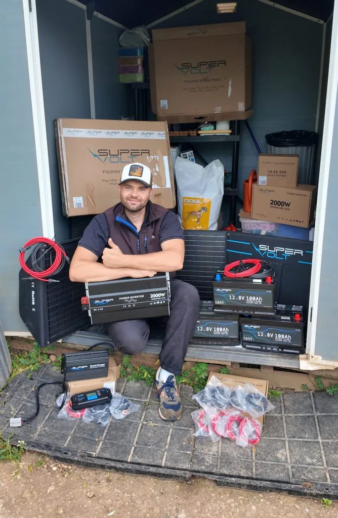 Die Bildcollage zeigt die Anlieferung und Installation von Supervolt-Komponenten für ein Tierschutzprojekt in Griechenland. Zu sehen sind LiFePO4-Batterien, Solartechnik, Wechselrichter und weiteres Zubehör für eine nachhaltige Offgrid-Stromversorgung. Im unteren Bereich sitzt Chris von adVANturetimewithus vor den gelieferten Komponenten. Das Projekt unterstützt die langfristige Energieversorgung eines Tierheims und verbessert die Lebensbedingungen für gerettete Hunde durch zuverlässige Beleuchtung und autarke Stromversorgung.