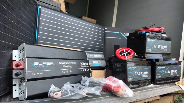 Die Bildcollage zeigt die Anlieferung und Installation von Supervolt-Komponenten für ein Tierschutzprojekt in Griechenland. Zu sehen sind LiFePO4-Batterien, Solartechnik, Wechselrichter und weiteres Zubehör für eine nachhaltige Offgrid-Stromversorgung. Im unteren Bereich sitzt Chris von adVANturetimewithus vor den gelieferten Komponenten. Das Projekt unterstützt die langfristige Energieversorgung eines Tierheims und verbessert die Lebensbedingungen für gerettete Hunde durch zuverlässige Beleuchtung und autarke Stromversorgung.